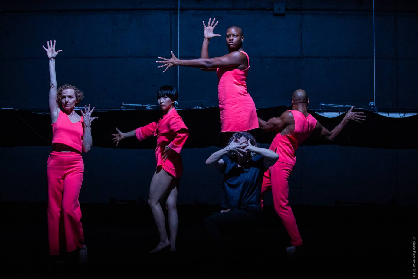 A group in bright pink makes voguing gestures with intense expressions